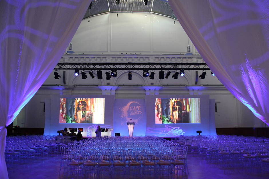 Corporate event stage setup with lighting and large screens